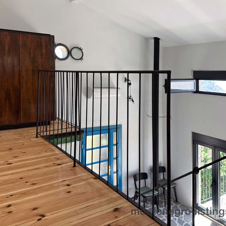 Elegant loft with wood floors, black metal railing, and large windows. Premier Ulcinj property listed by immorenta.me (ekosphere doo).