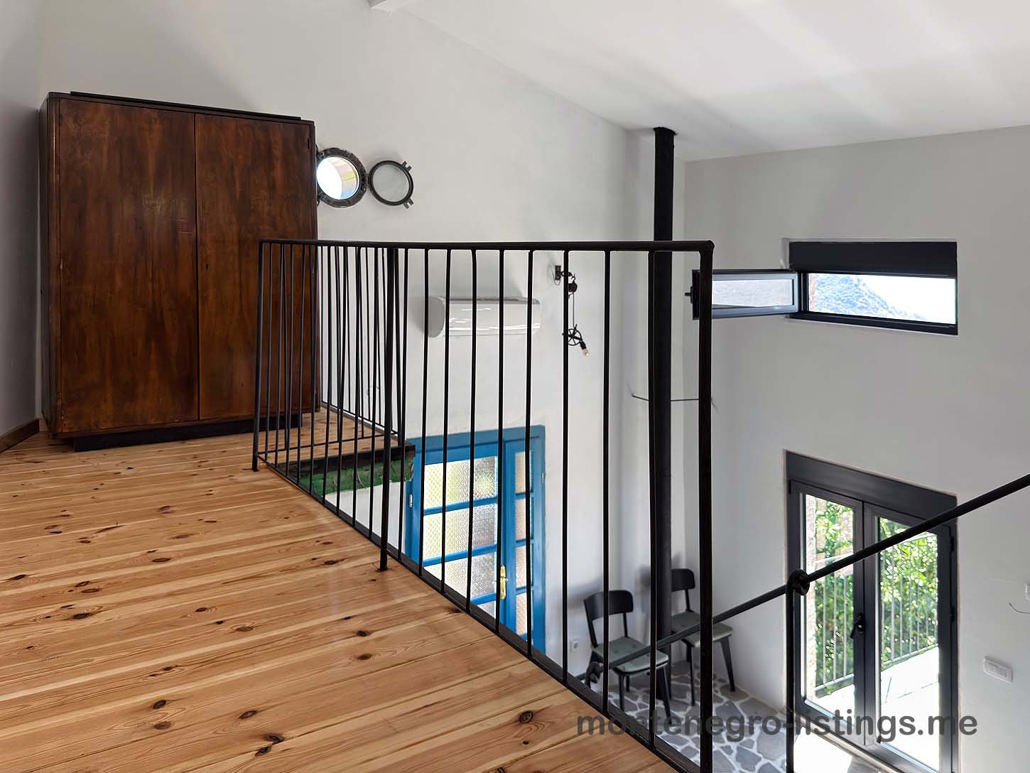 Elegant loft with wood floors, black metal railing, and large windows. Premier Ulcinj property listed by immorenta.me (ekosphere doo).