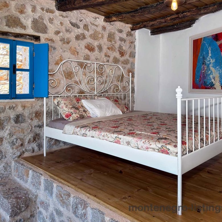 Charming Ulcinj property: stone-walled room, stylish white bed, wood platform&mdash;invest in Montenegro with immorenta.me by ekosphere doo.