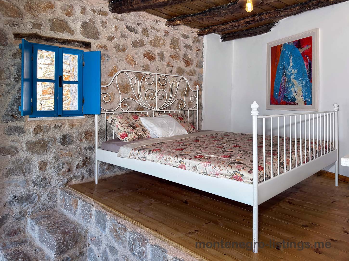 Charming Ulcinj property: stone-walled room, stylish white bed, wood platform&mdash;invest in Montenegro with immorenta.me by ekosphere doo.