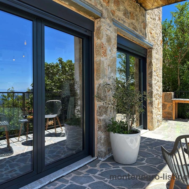 Elegant stone patio with sliding doors, stylish seating, and scenic views&mdash;prime Ulcinj Montenegro real estate by Ekosphere on immorenta.me.