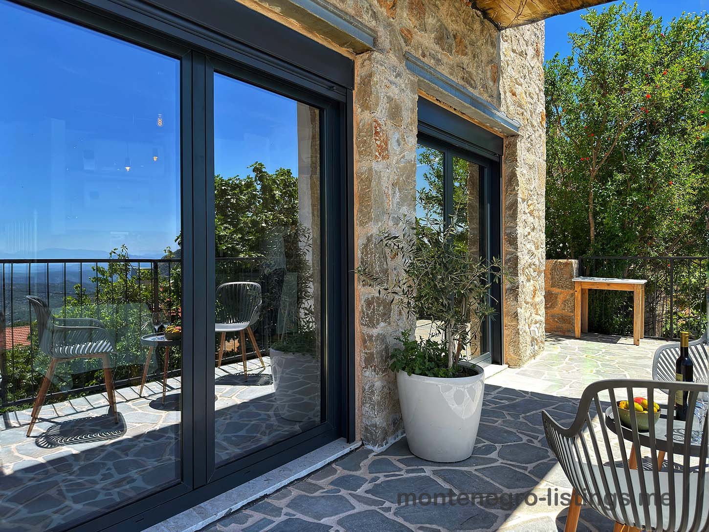 Elegant stone patio with sliding doors, stylish seating, and scenic views&mdash;prime Ulcinj Montenegro real estate by Ekosphere on immorenta.me.