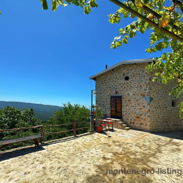 Stone house with wooden door, sunlit patio, greenery; top Ulcinj real estate by immorenta.me & ekosphere doo. Invest now!.