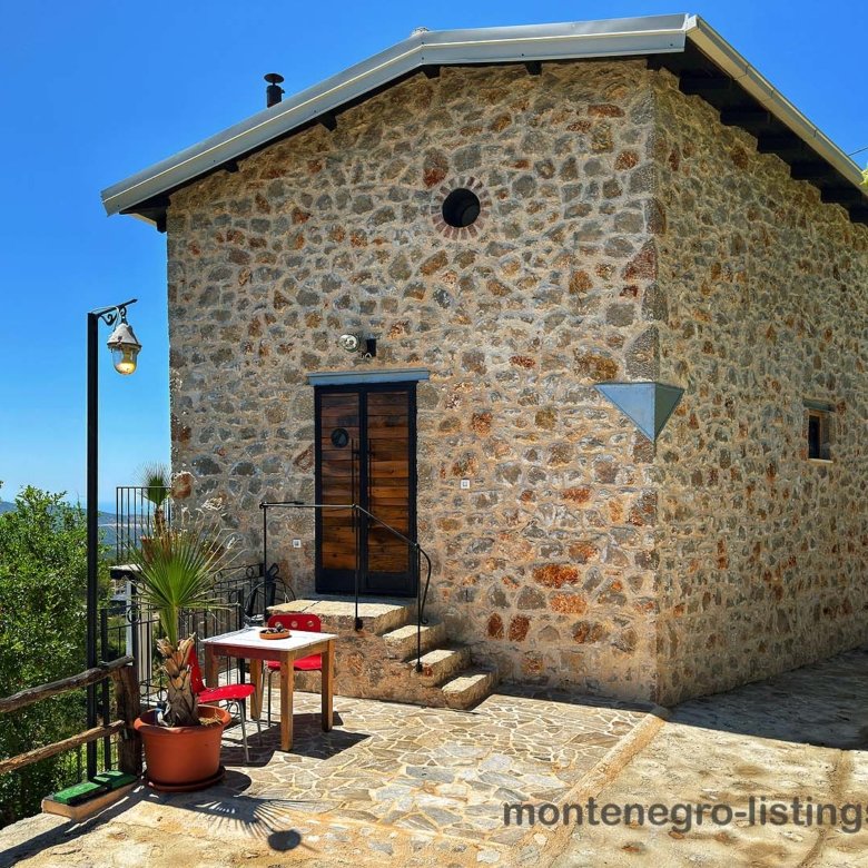 Charming stone house with black door, lush green surroundings, and stone terrace in Ulcinj, Montenegro. immorenta.me by ekosphere doo.