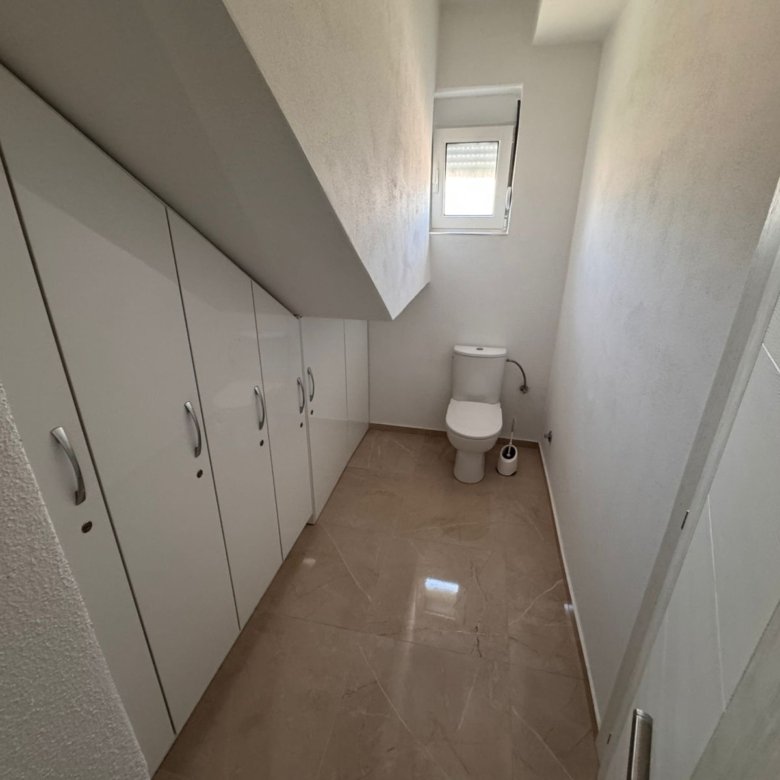 Modern narrow bathroom with slanted ceiling, elegant built-ins, and sleek tiling&mdash;exclusive Ulcinj property via immorenta.me by Ekosphere.