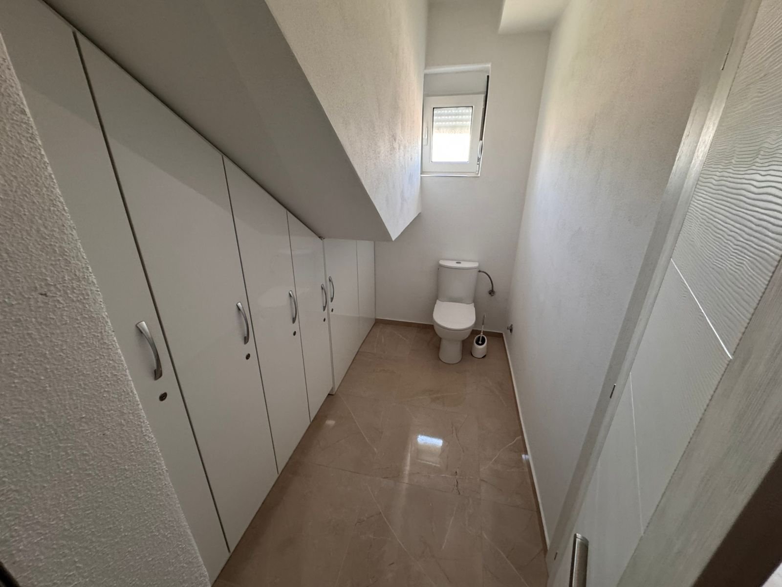 Modern narrow bathroom with slanted ceiling, elegant built-ins, and sleek tiling&mdash;exclusive Ulcinj property via immorenta.me by Ekosphere.