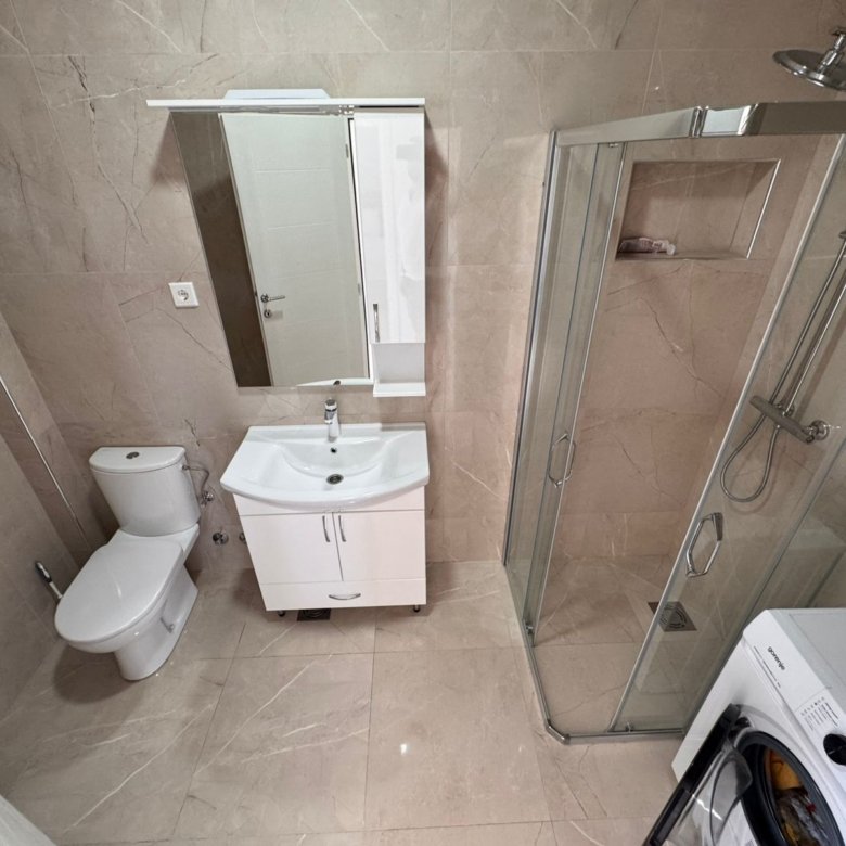 Contemporary bathroom in Ulcinj with beige tiles, glass shower, vanity, washer&mdash;ideal property investment listed at immorenta.me by ekosphere doo.