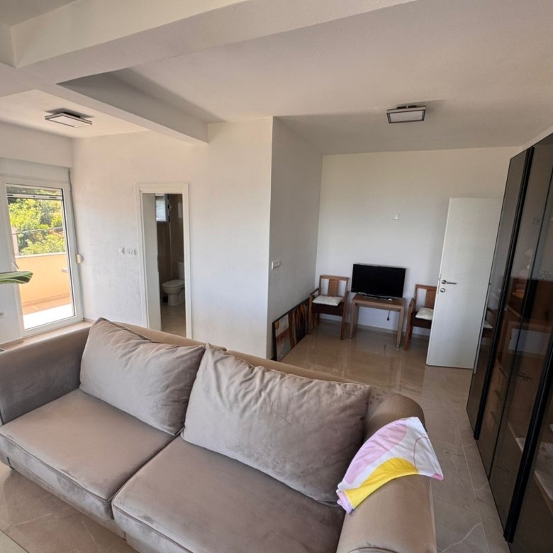 Modern Ulcinj apartment: bright living room, chic beige sofa, balcony access, and bathroom&mdash;exclusive on immorenta.me by ekosphere.