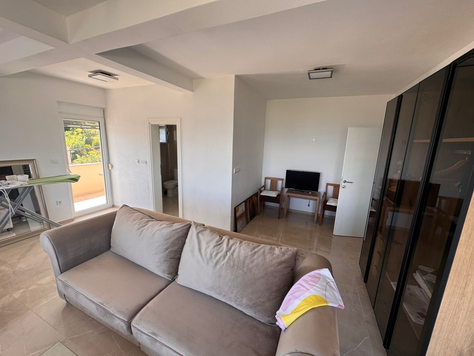 Modern Ulcinj apartment: bright living room, chic beige sofa, balcony access, and bathroom&mdash;exclusive on immorenta.me by ekosphere.