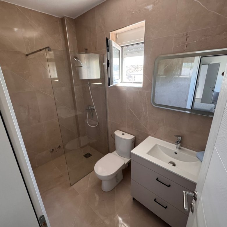 Luxurious Ulcinj bathroom: beige marble, glass shower, modern sink, bright window&mdash;exclusive at immorenta.me by ekosphere doo.