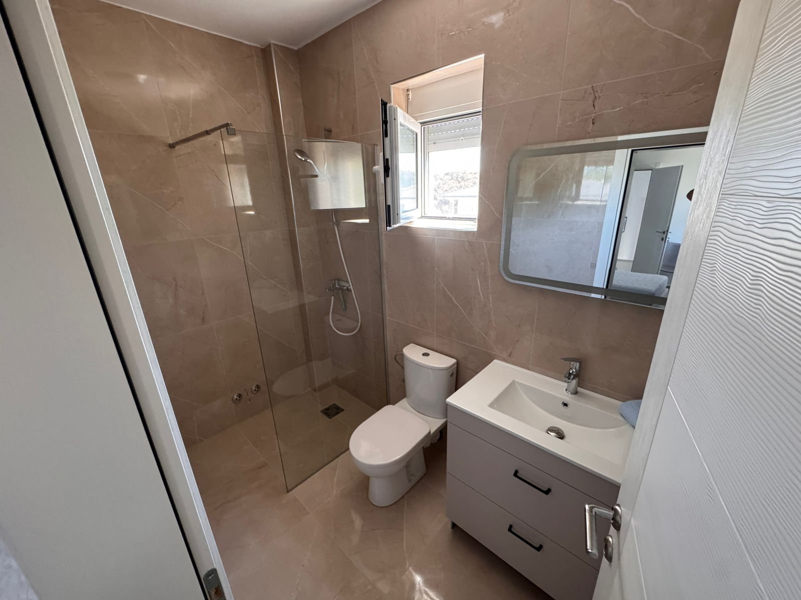 Luxurious Ulcinj bathroom: beige marble, glass shower, modern sink, bright window&mdash;exclusive at immorenta.me by ekosphere doo.