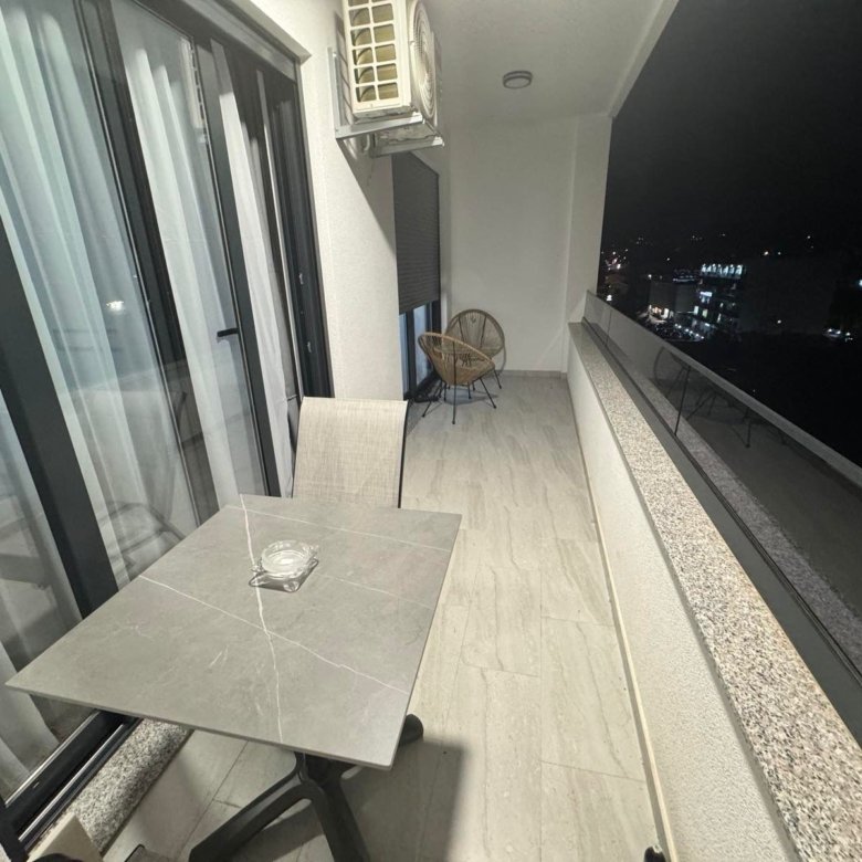 Luxury Ulcinj balcony: marble table, air conditioning, chic wicker seating, city views. Prime investment on immorenta.me.