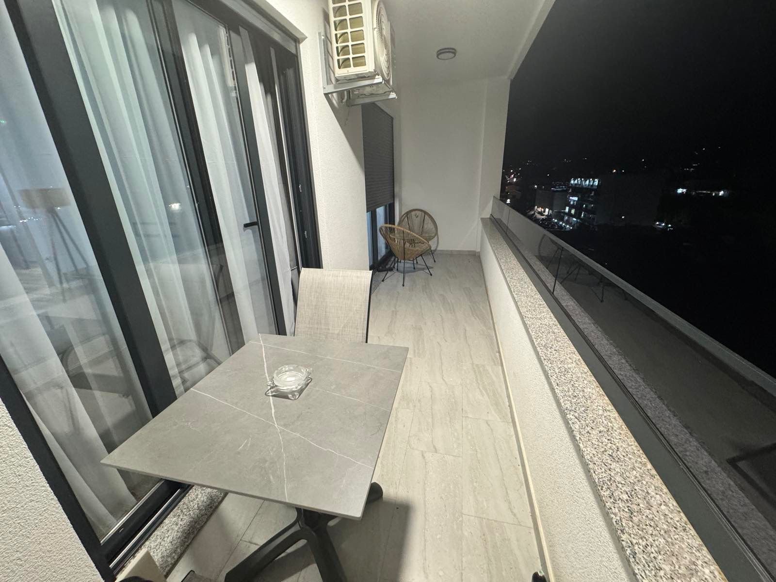 Luxury Ulcinj balcony: marble table, air conditioning, chic wicker seating, city views. Prime investment on immorenta.me.