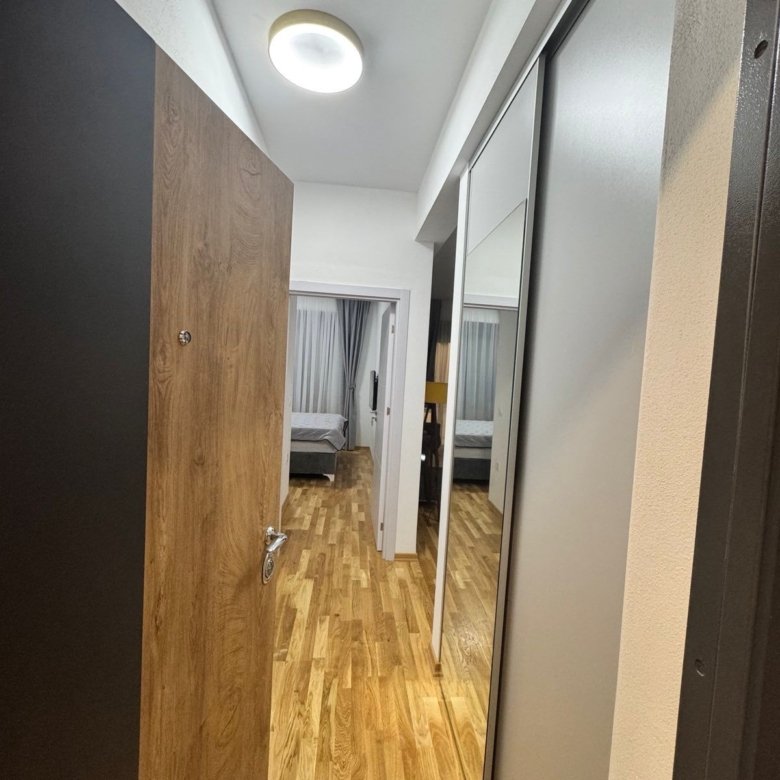 Elegant Ulcinj apartment hallway with wood floors, mirrored closets, spacious bedroom. Invest via immorenta.me by ekosphere doo.