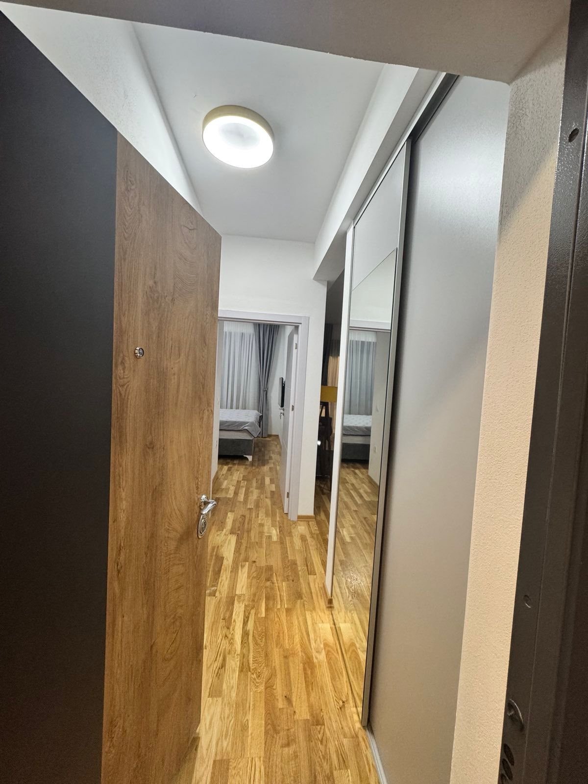 Elegant Ulcinj apartment hallway with wood floors, mirrored closets, spacious bedroom. Invest via immorenta.me by ekosphere doo.