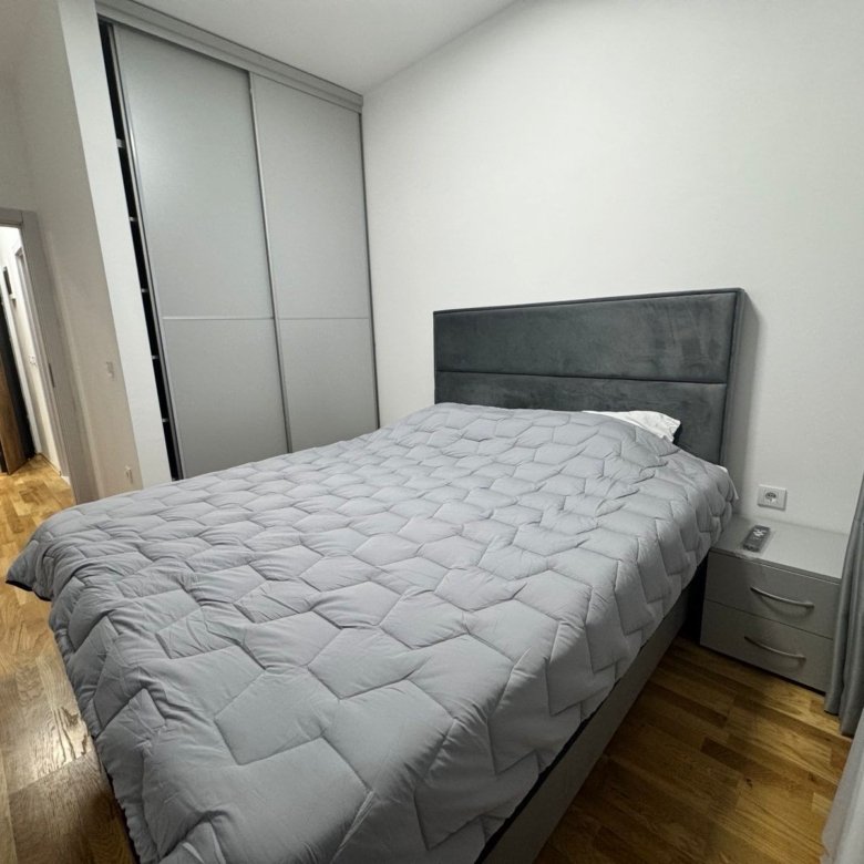 Elegant Ulcinj bedroom with stylish gray-quilted bed, hardwood floors, spacious closets&mdash;ideal Montenegro investment via immorenta.me by ekosphere doo.