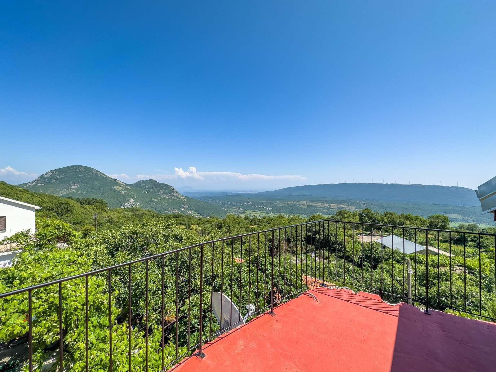 Listings for Sale - Stunning red terrace with black metal railing, panoramic green hills, and mountain views&mdash;prime real estate in Ulcinj, Montenegro.