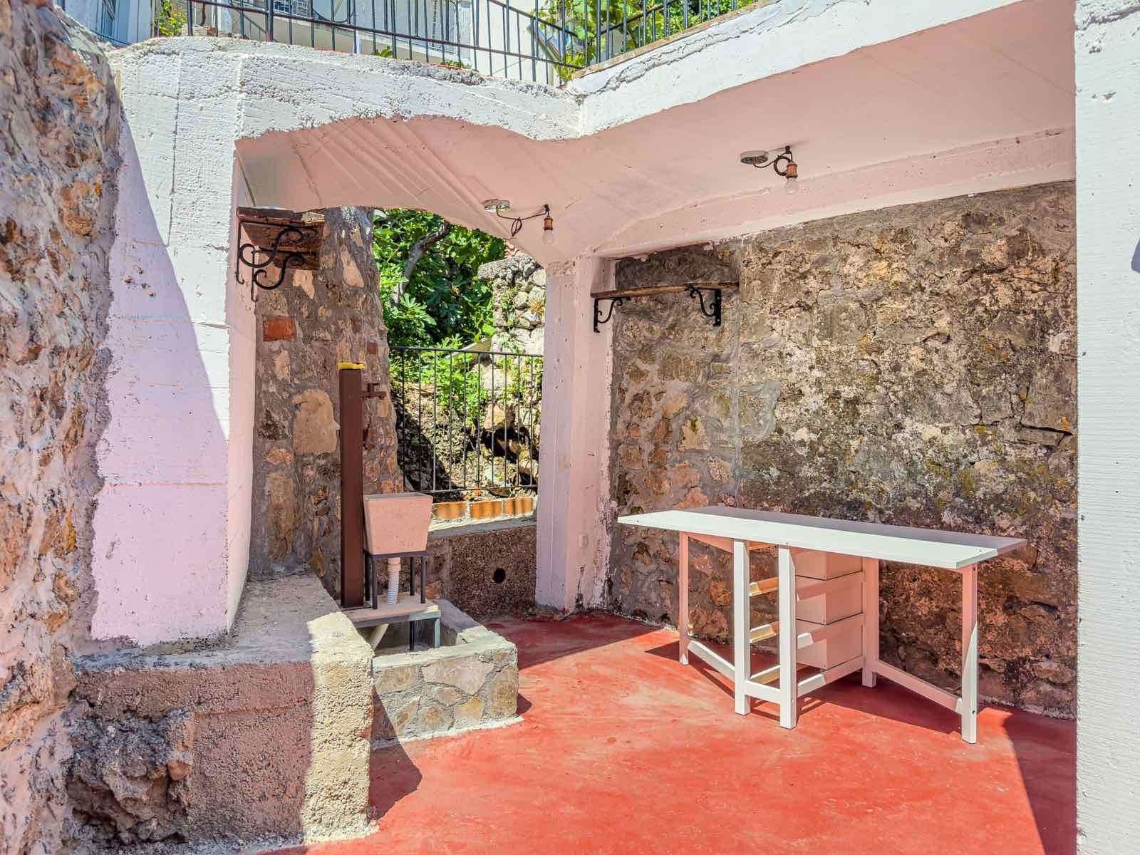 Stunning shaded outdoor area in Ulcinj with stone walls, red flooring, and stylish fixtures&mdash;ideal Montenegro investment by ekosphere doo.