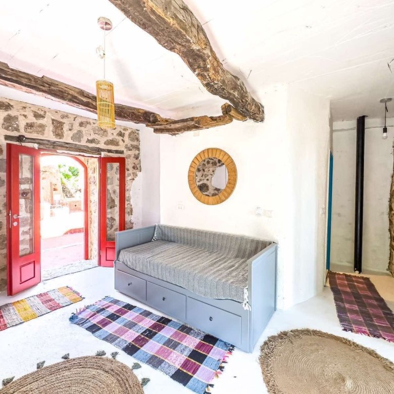 Experience authentic Ulcinj living: rustic stone walls, wood beams, vibrant decor, sunlit daybed; exclusive at immorenta.me.