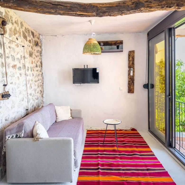 Listings for Rent in Ulcinj: Modern Ulcinj living room: grey sofa, stylish rug, exposed beams, stone accents, balcony with views&mdash;exclusive at immorenta.me.