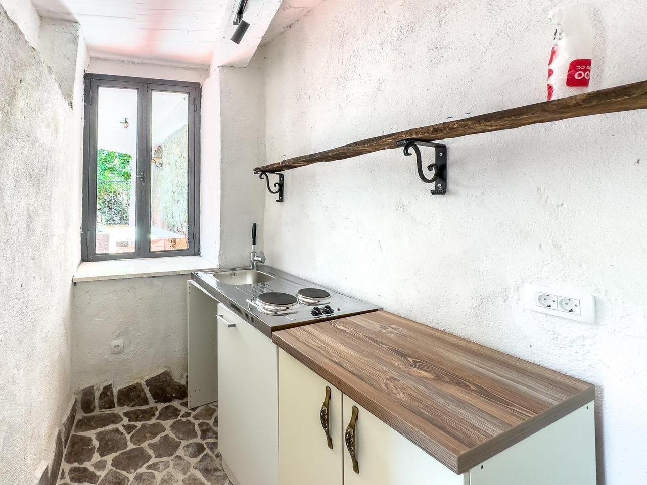 Charming Ulcinj kitchen: stone floors, white textured walls, bright window. Ideal investment via immorenta.me by ekosphere doo.