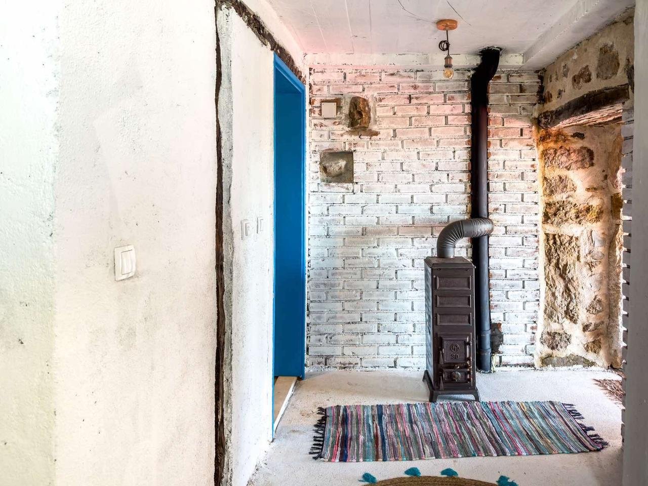 Charming Ulcinj retreat with whitewashed brick walls, wood stove, blue door & stone accents. Exclusive at immorenta.me by ekosphere doo.