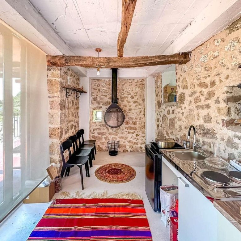 Charming Ulcinj rustic kitchen with stone walls, fireplace, appliances, and natural light. Exclusive listing by ekosphere doo.