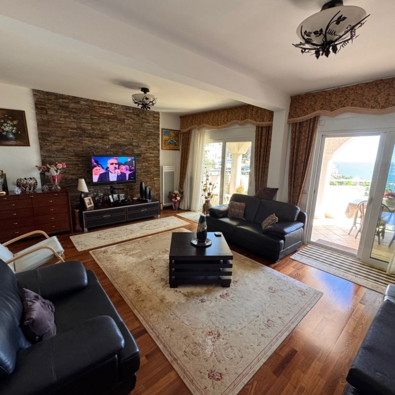 Elegant Ulcinj living room: black leather sofas, TV, stone wall, sea-view balcony. Invest via immorenta.me by ekosphere doo.