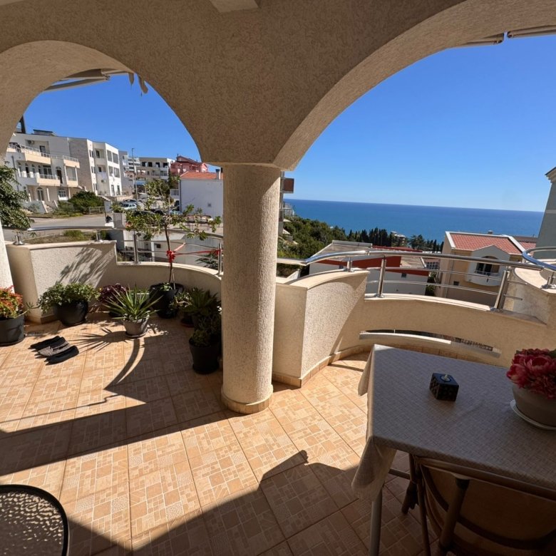 Spacious tiled balcony in Ulcinj with sea view, stylish columns, lush potted plants&mdash;exclusive property by immorenta.me.