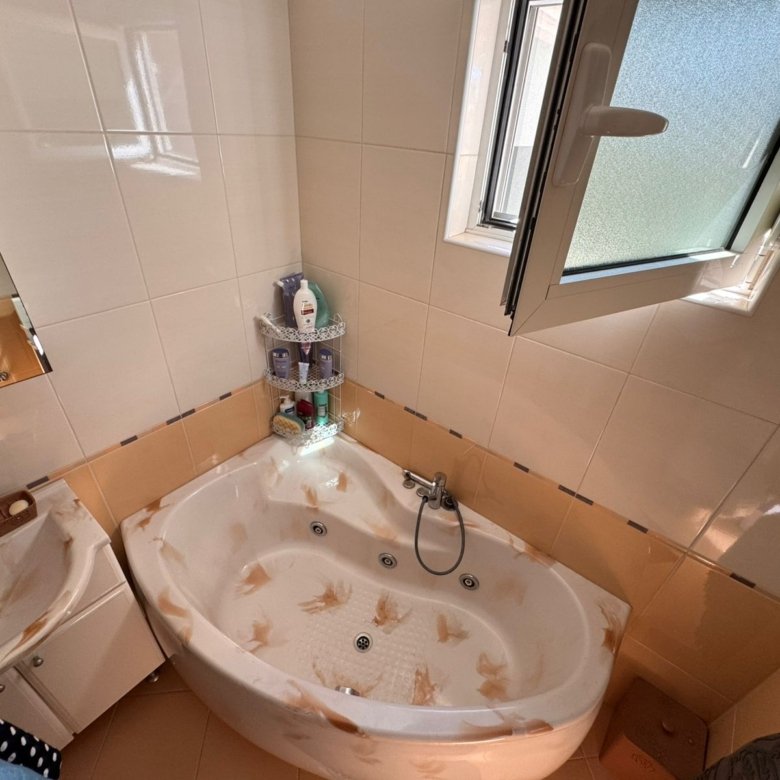 Modern tiled bathroom in Ulcinj with a sunlit corner bathtub, quality fixtures, and window&mdash;ideal Montenegro investment by ekosphere doo.