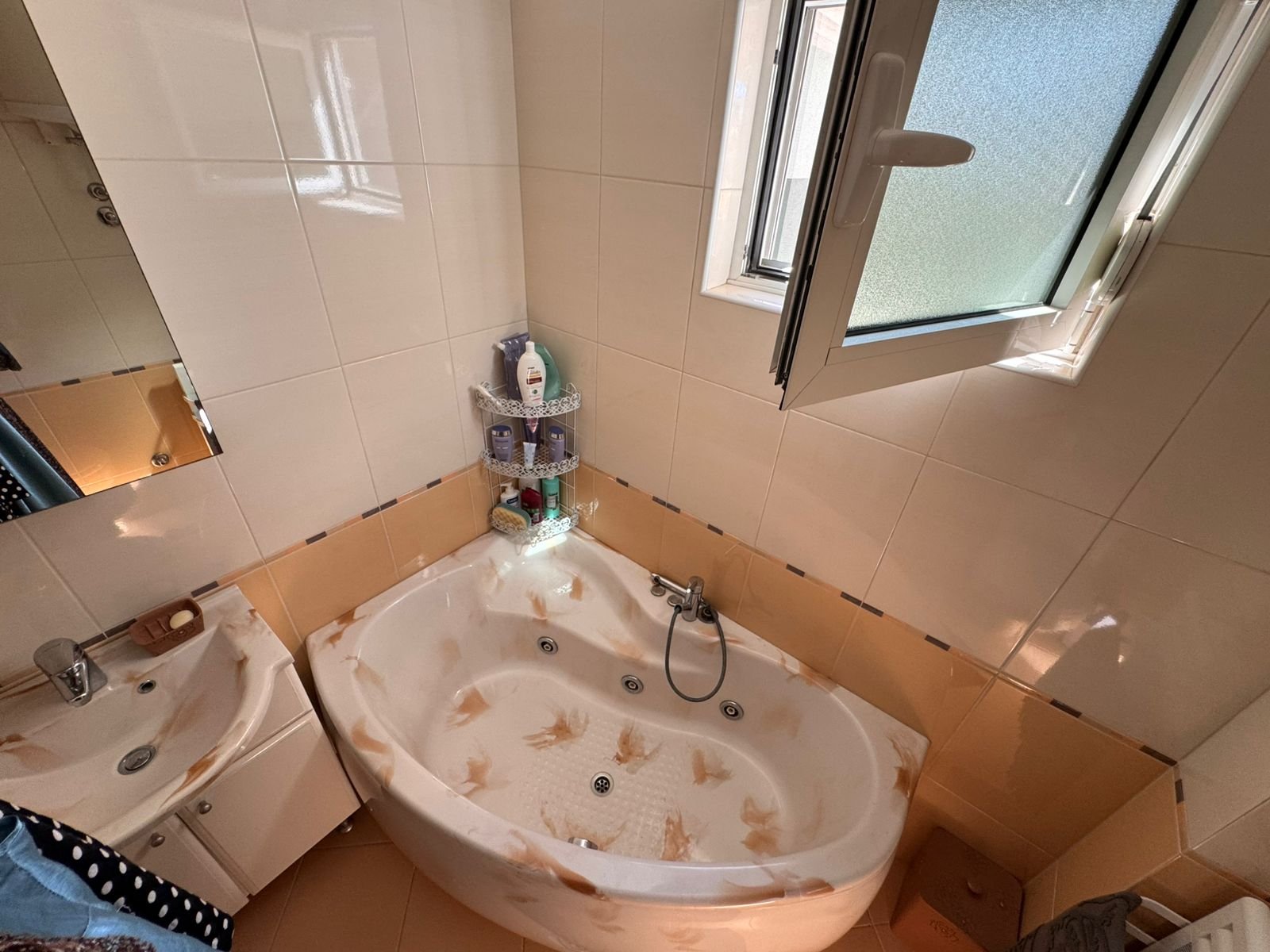 Modern tiled bathroom in Ulcinj with a sunlit corner bathtub, quality fixtures, and window&mdash;ideal Montenegro investment by ekosphere doo.