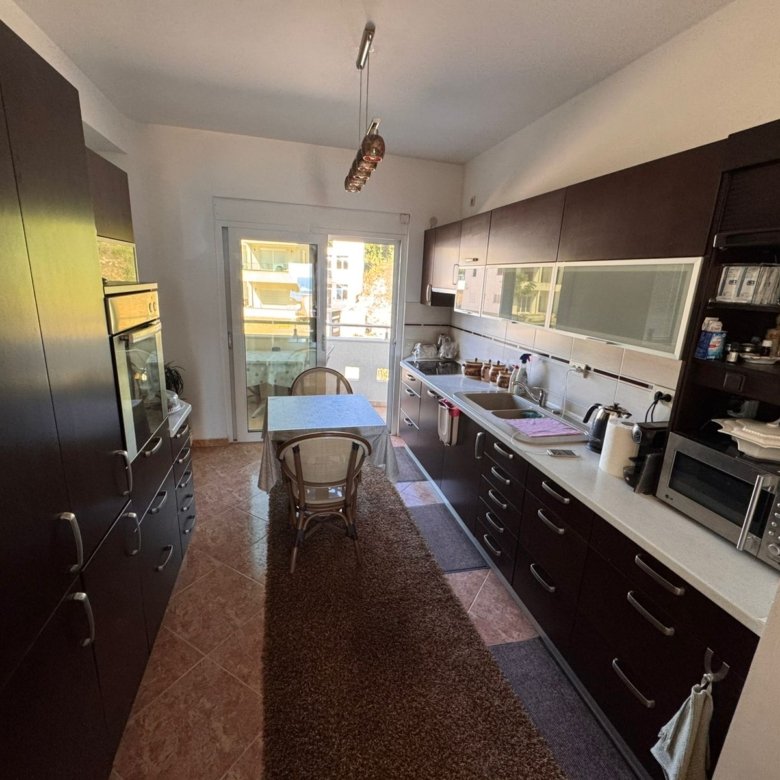 Elegant Ulcinj kitchen with sleek dark cabinets, sunlit dining area, premium appliances&mdash;ideal Montenegro property investment. Exclusive by ekosphere doo via immorenta.me.