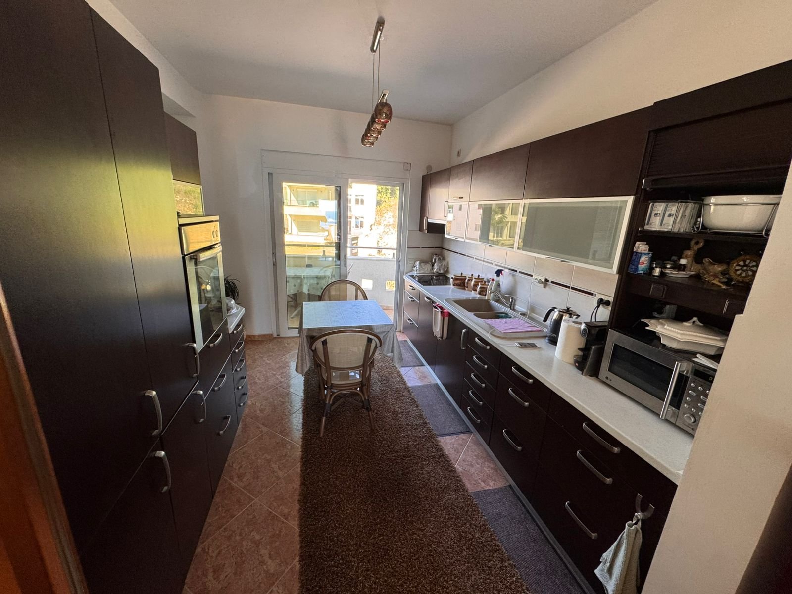 Elegant Ulcinj kitchen with sleek dark cabinets, sunlit dining area, premium appliances&mdash;ideal Montenegro property investment. Exclusive by ekosphere doo via immorenta.me.