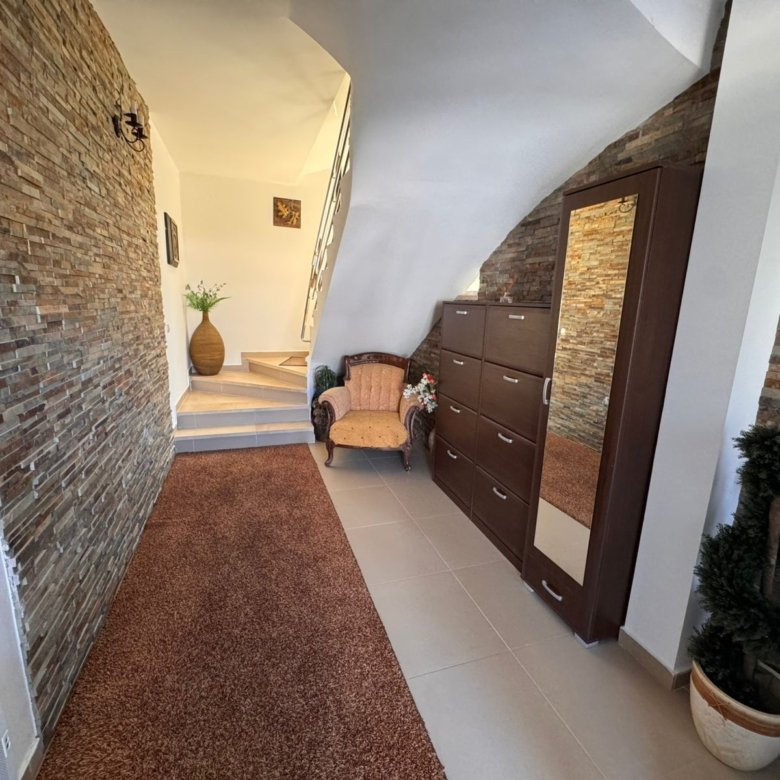 Elegant Ulcinj home with stone accents, plush chair, wood dresser, modern lighting; premium real estate on immorenta.me.