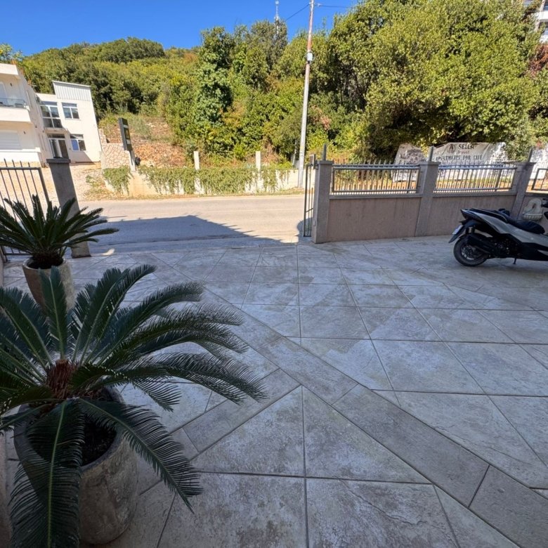 Modern tiled patio featuring lush potted greenery, secure metal fencing, and urban Ulcinj views&mdash;exclusive at immorenta.me by ekosphere doo.