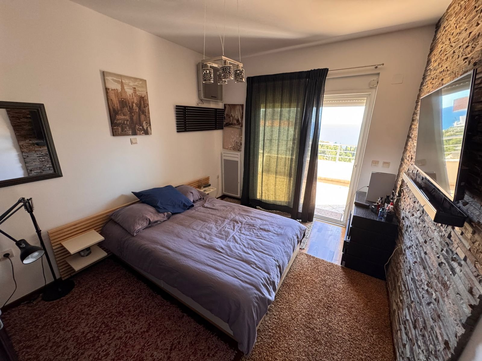 Modern Ulcinj bedroom with gray double bed, balcony view, TV, and desk&mdash;ideal Montenegro real estate from ekosphere doo.