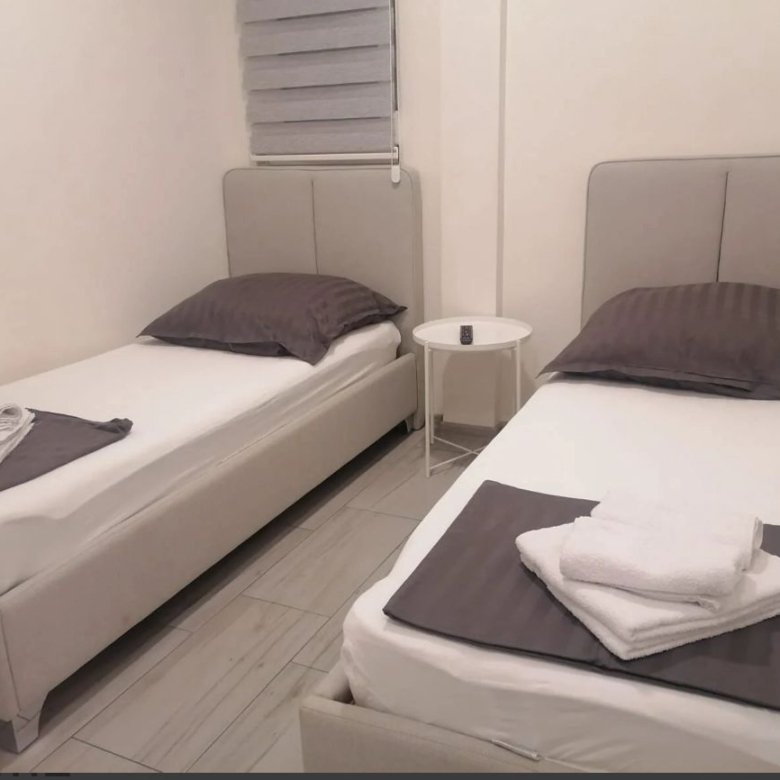 Modern Ulcinj property: twin beds with stylish grey headboards, crisp linens, and elegant decor&mdash;ideal Montenegro investment. Powered by ekosphere doo on immorenta.me.