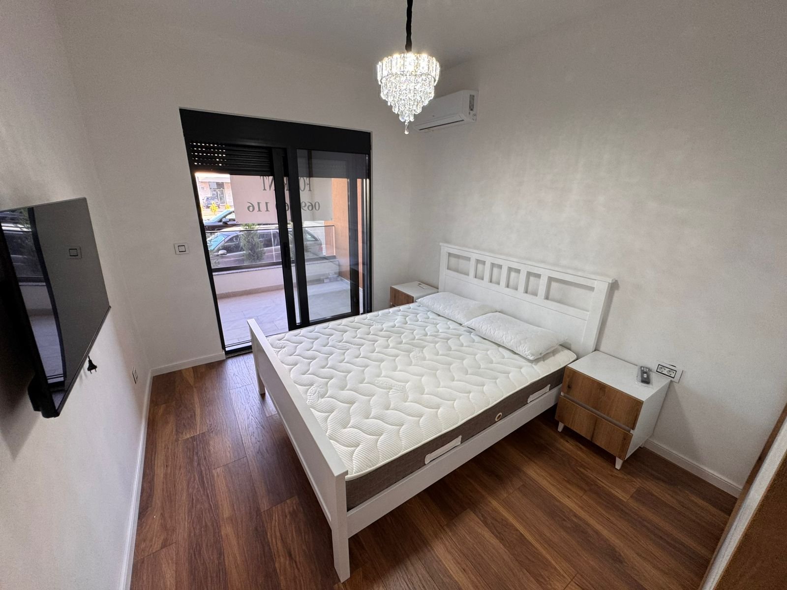Modern Ulcinj bedroom with double bed, AC, TV, chandelier, and balcony access&mdash;prime real estate by immorenta.me/Ekosphere doo.