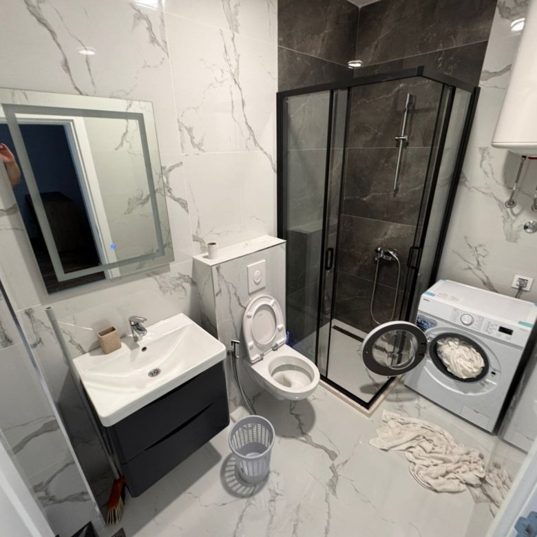 Sleek Ulcinj bathroom: white marble, glass shower, wall toilet, washer, premium amenities&mdash;ideal Montenegro investment. Eksophere doo project.