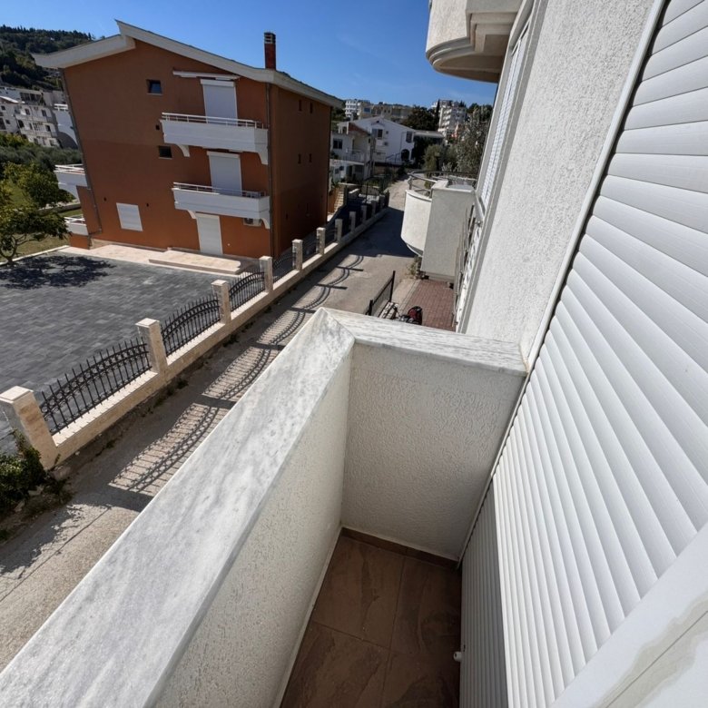 Stunning marble-railed balcony view over a serene Ulcinj street, lush greenery, quality apartments&mdash;exclusive at immorenta.me by ekosphere doo.