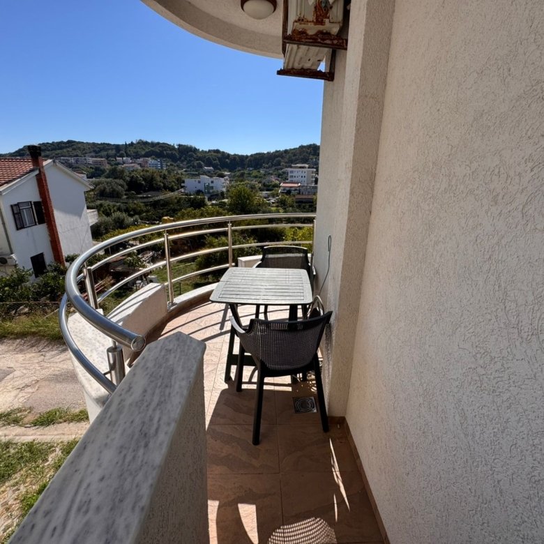 Charming Ulcinj balcony with glass-top table, seating for two, scenic hills, and tranquil views&mdash;exclusive on immorenta.me by ekosphere doo.