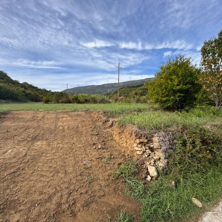 Prime Ulcinj land for sale: cleared plot with lush grassy area, trees, hill views, and infrastructure&mdash;exclusive on immorenta.me.