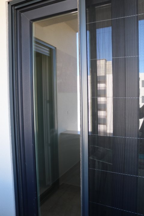 Modern sliding glass door with mesh screen opens to balcony; enjoy Ulcinj views. Exclusive via immorenta.me by ekosphere doo.