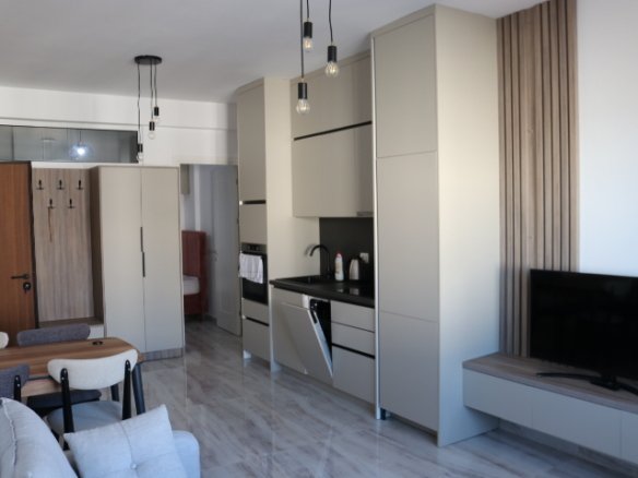 Modern Ulcinj apartment: light cabinetry, built-ins, designer lighting, wall TV, dining set, gray sofa. Exclusive at immorenta.me by ekosphere doo.