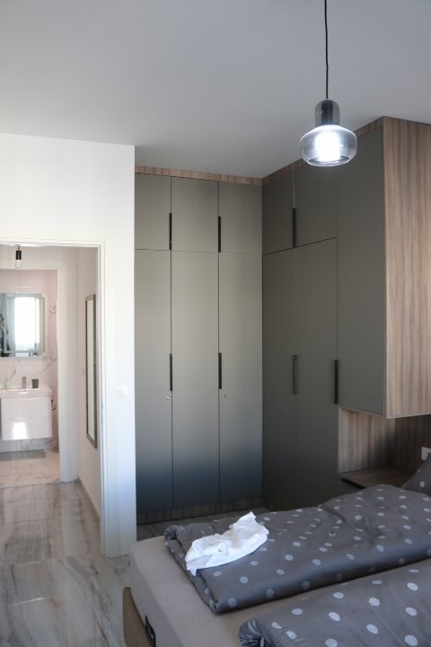 Elegant Ulcinj bedroom with sleek gray wardrobes, stylish polka dot bedding, ensuite bath&mdash;ideal Montenegro property investment.