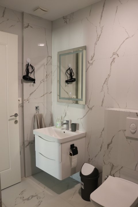 Sleek Ulcinj bathroom with marble walls, modern fixtures, luxury sink, and amenities. Invest in Montenegro real estate at immorenta.me by ekosphere doo.