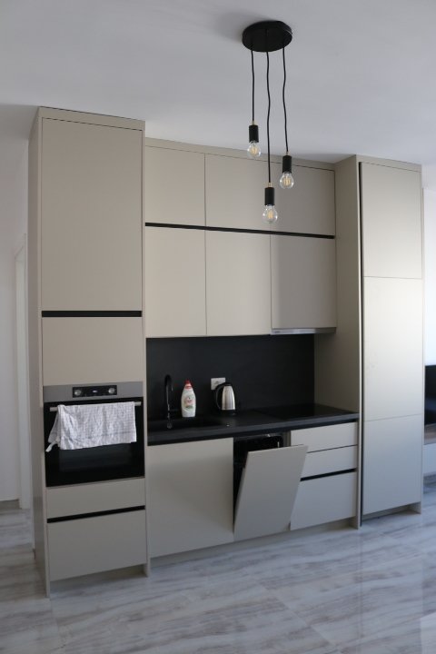 Sleek modern kitchen in Ulcinj, Montenegro: beige cabinets, black counters, oven, open dishwasher. Listed on immorenta.me by ekosphere doo.
