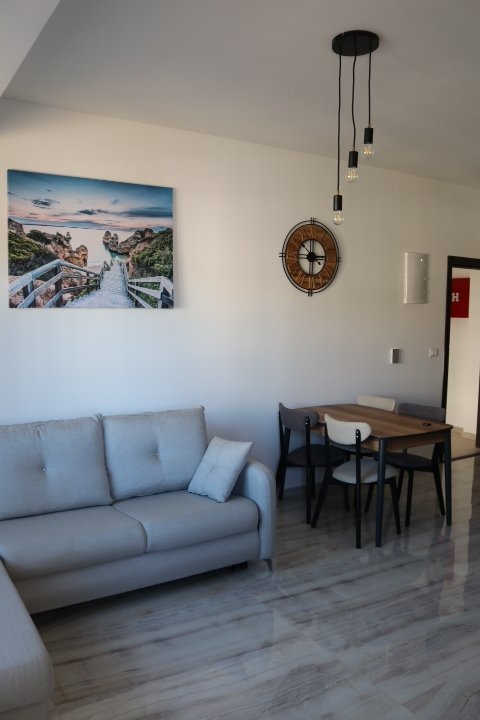 Elegant Ulcinj apartment: modern living room, gray sofa, marble floors, dining area. Invest at immorenta.me by ekosphere doo.