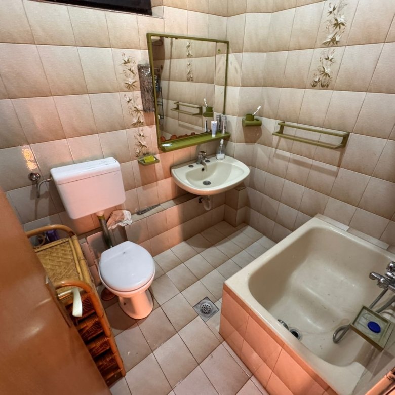 Modern bathroom with tan tile, bathtub, mirror, and ample storage&mdash;ideal Ulcinj investment. Discover more at immorenta.me.