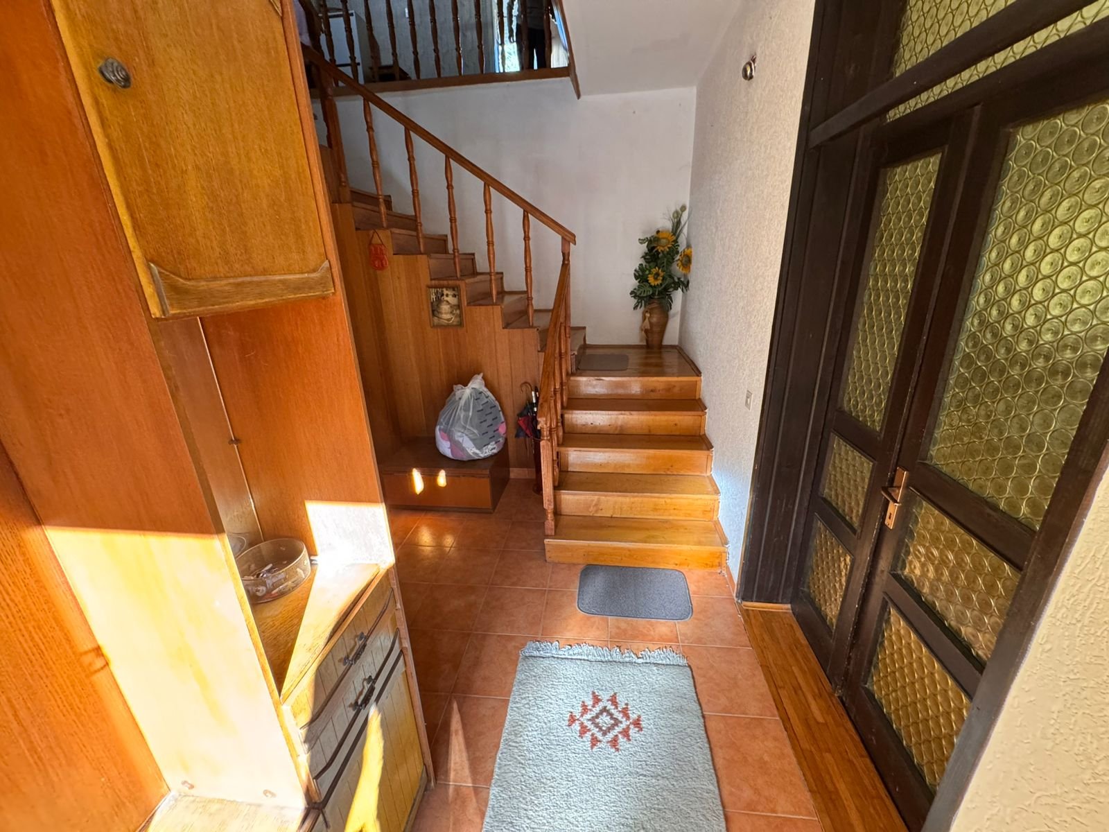 Elegant Ulcinj hallway with wood stairs, tiled floors, glass-paneled door, and premium finishes. Montenegro-listings.me by ekosphere doo.